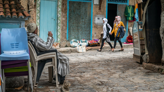 Unidentified man sitting on a chair in blue medina of Chefchaouen city in Morocco, North Africa
