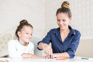 Fototapeta premium Happy family. Mother and daughter together paint and draw. Adult woman helps the child girl