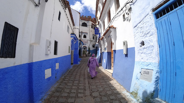 Unidentified woman walking in blue medina of Chefchaouen city in Morocco, North Africa