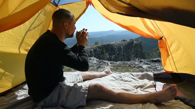 Man drinks from a mug in an camping outdoor