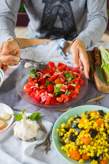 Woman hands holds vegetarian lunch with fresh red tomatoes and salad leaves, cooked vegetables, boiled corn grain, eggplants, carrots. Vegan dinner and healthy food