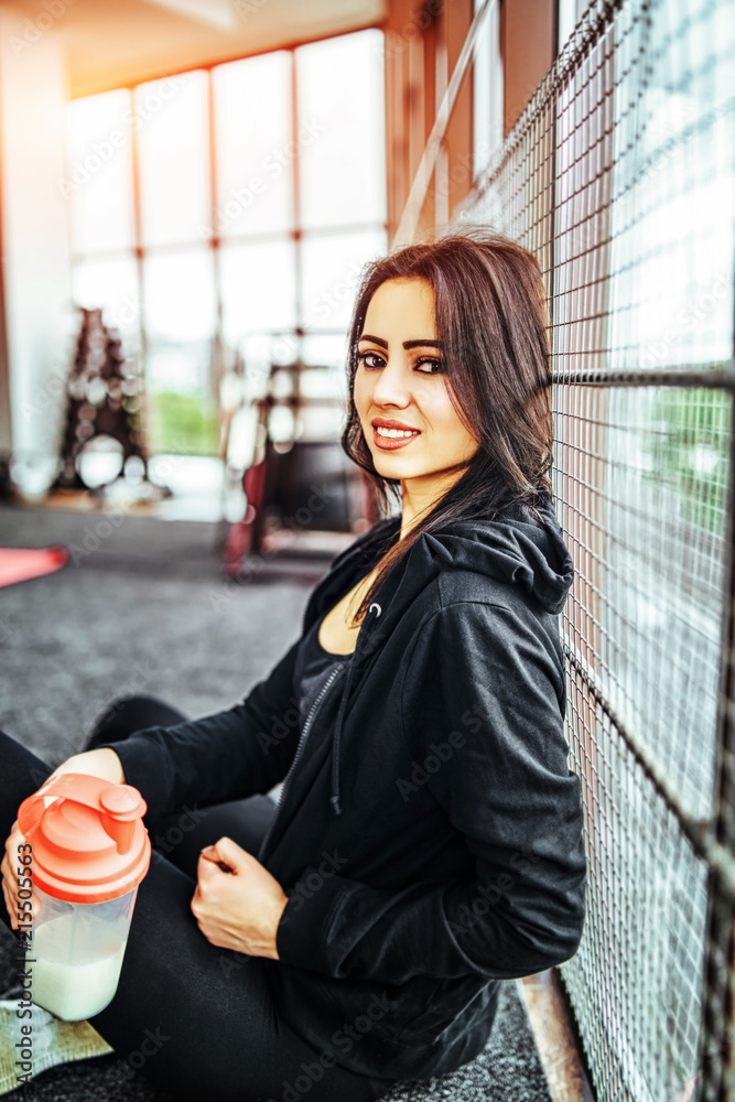 Wall mural Cute sporty girl sitting in the gym