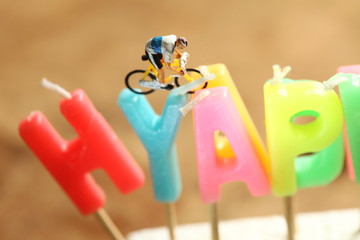 Miniature plastic made cycling figure model and birthday candle scene. 
