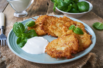 Fried potato fritters with sour cream and basil