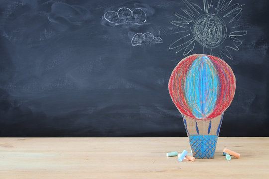 Back to school concept. cardboard handmade hot air balloon over classroom blackboard background.