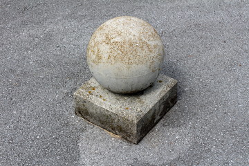 Fototapeta na wymiar Concrete grey sphere on rectangle foundation parking security barrier or bollard mounted on asphalt parking lot edge