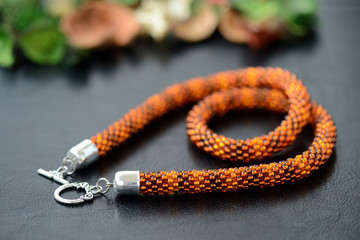 Bead crochet necklace amber color on a dark background close up