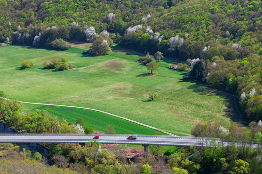 Straße mit Autos durch grüne bewaldete Landschaft
