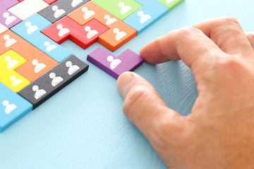 image of tangram puzzle blocks with people icons over wooden table ,human resources and management...