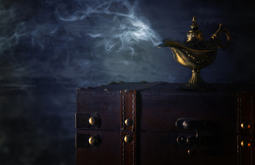 Image of magical mysterious aladdin lamp with smoke over black background. Lamp of wishes.