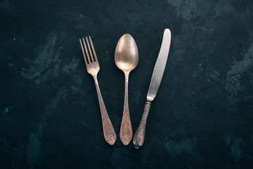 Old cutlery. On a black stone background. Top view. Free space for text.