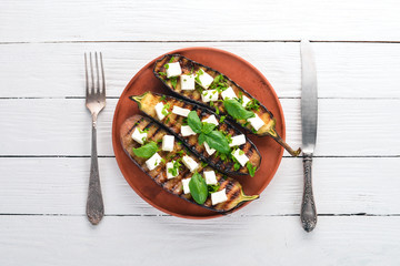 Eggplant grilled with feta cheese and basil. Healthy food. On a white wooden table. Top view. Free space for text.