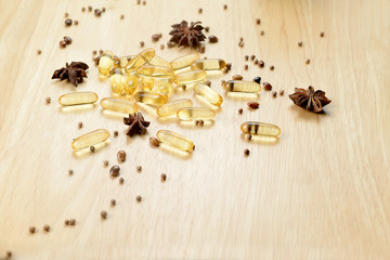Fototapeta na wymiar Medicine herb, Cod liver oil omega 3 gel capsules on wooden brown tone background