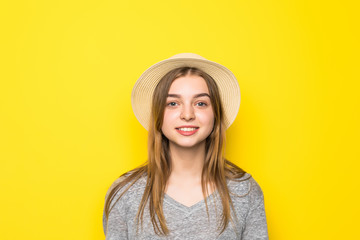 Beautiful beauty young woman in gray shirt and straw hat on yellow background.