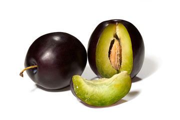Ripe black plums with slice on a white background