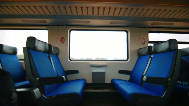 Clip inside a passenger wagon of two empty rows of seats and a window, while the train is moving, Netherlands.