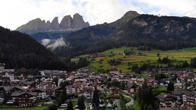 Aerial view from drone Campitello Di Fasa, Dolomites, Italy. Rocky mountains in the background. Italian Dolomites Mountains Village.  Canazei