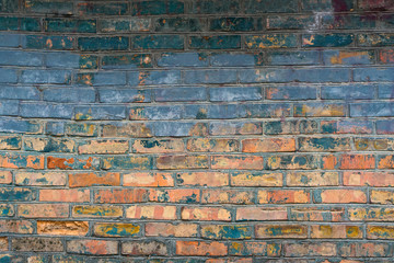 Very old brick wall many times repainted with different colors