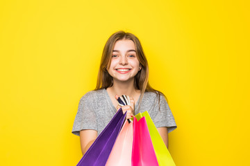 Fototapeta na wymiar Young shopping woman with colored packages on a yellow background