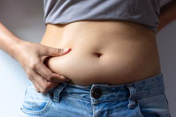Naklejka premium woman with overweight abdomen. hand holding excessive fat belly ,front view