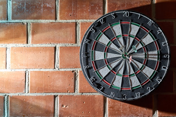 Dartboard on a brick wall. 3 darts in the bullseye. 150 bullseye