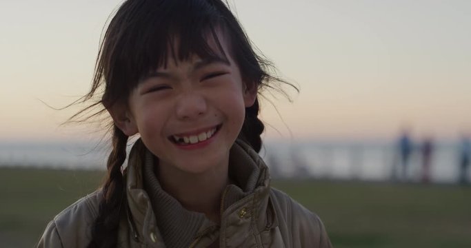 portrait of little asian girl laughing cheerful enjoying happy summer vacation on seaside park