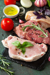 Fresh raw meat. Different types of raw pork meat, chicken fillet and beef with vegetables and herbs on dark wooden background. Copy space.