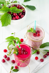 Raspberry and Cherry milkshake or smoothie on a white wooden background. Healthy juicy vitamin drink diet or vegan food concept. Copy space.