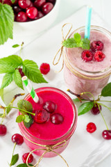 Raspberry and Cherry milkshake or smoothie on a white wooden background. Healthy juicy vitamin drink diet or vegan food concept.