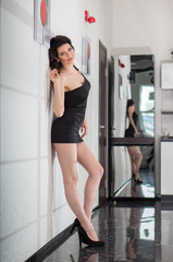 sexy girl in a black dress stands in the modern interior