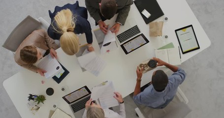 professional multi ethnic business team sharing ideas in boardroom meeting brainstorming corporate strategy using market statistics in documents top view