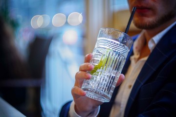 man drinks an alcoholic cocktail in the evening in the city.