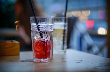 red alcohol cocktail in a glass cup, night city.