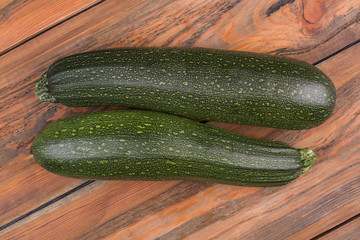 Two zuccini on wood. Fresh green zucchini, brown wood background.