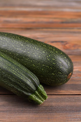 Raven zucchini close up. Brown wooden background.