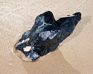 Morion Smokey Quartz with Chlorite lying on wet sand  in front of the lake at sunrise.