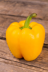 Fresh yellow a pepper on rustic wooden background. Dew drops. Close up.