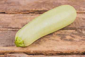 Bright squash vegetable marrow zucchini. Whole pale courgette. Old vintage wooden table background.