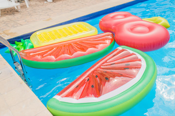 inflatable mattresses in the pool in the form of watermelon, pineapple and cherry