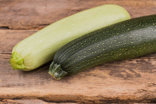 Two whole raw fresh zucchini. Green and pale green courgettes on wood.
