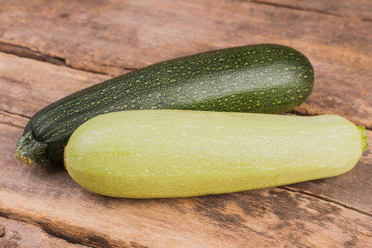 Two squash vegetable marrow zucchini. Close up. Old vintage wooden desk background.
