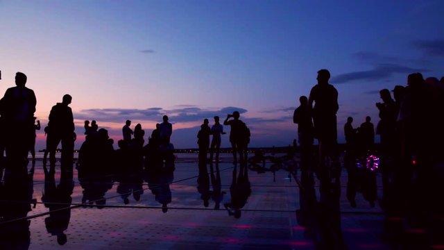 Silhouette group of people enjoy the  moment on greet the sun during sunset time  in Zadar, Croatia