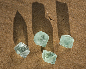 Green Fluorite Natural Octahedron Crystals on the beach at sunrise.