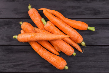 Pile of ripe carrots top view. Dark wooden backgroound. Black table.