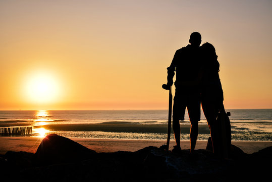 jeune couple face au soleil couchant