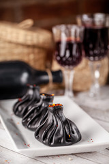 Traditional Georgian and Armenian cuisine. Trend, Georgian black khinkali with meat and suluguni cheese, on a wooden table in a restaurant. Wine on the table. Copy space, selective focus