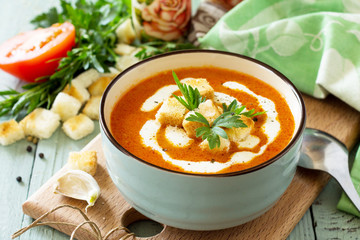 Diet menu. Puree soup tomato with croutons and cream in a bowl on a kitchen wooden table. The concept of healthy eating.
