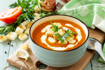 Diet menu. Puree soup tomato with croutons and cream in a bowl on a kitchen wooden table. The...