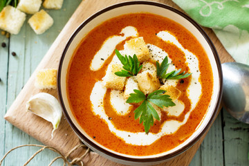 Puree soup tomato with croutons and cream in a bowl close-up on a kitchen wooden table. Diet menu. The concept of healthy eating.