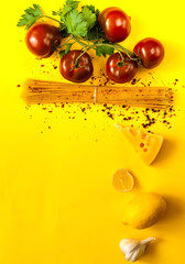 tomatoes kumato and ingredients for cooking pasta on yellow background. Frame made of organic products. Concept of vegetarian food and healthy eating.Flat lay, copy space, close up.